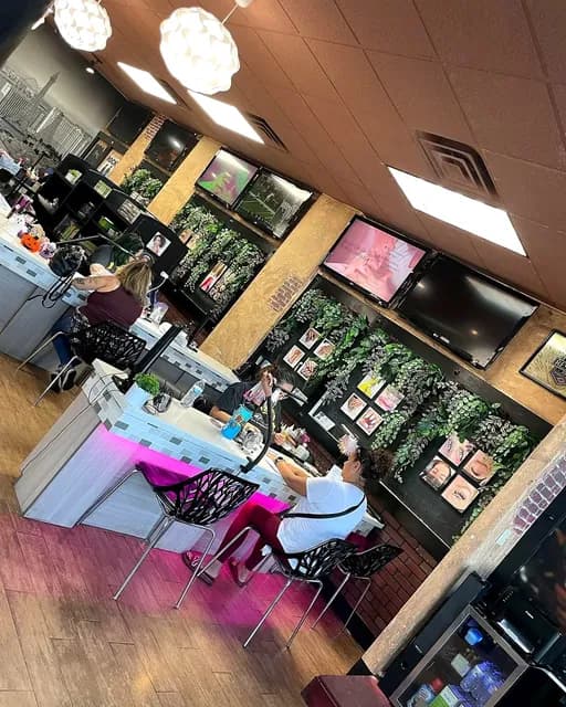 Overhead view of the front of the salon, with a client in the pink-lit lounge and framed lash photos on the wall