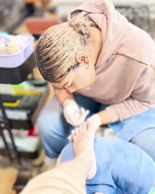 Nail tech bent over a clientβs pedicure at the spa chairs