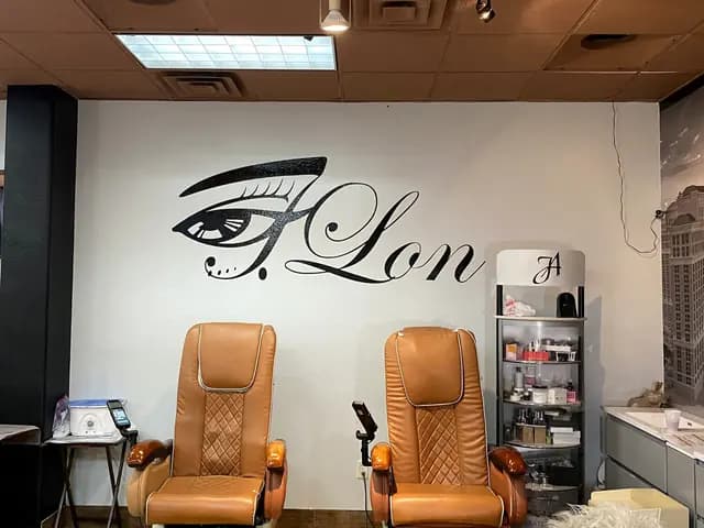 Two tan spa chairs in front of the painted J.Lon eye logo wall