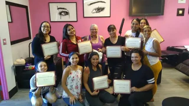 Academy graduates holding their certificates in front of the pink training-room wall