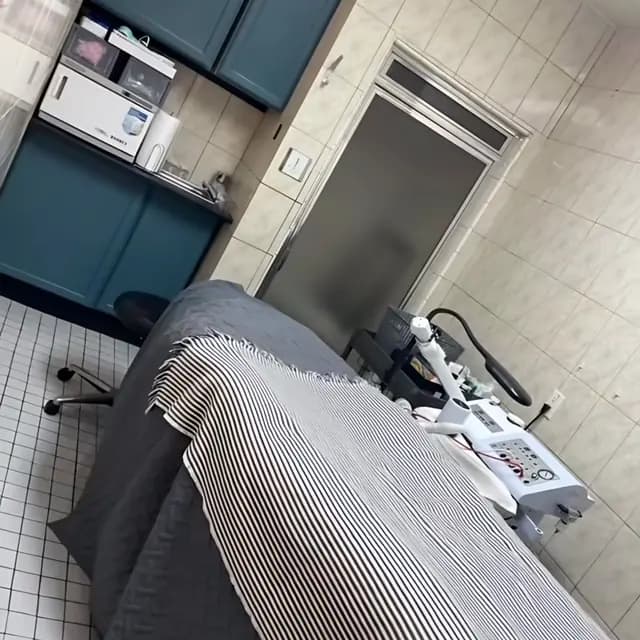 Private treatment room with a striped blanket on the bed and a skin-care machine alongside