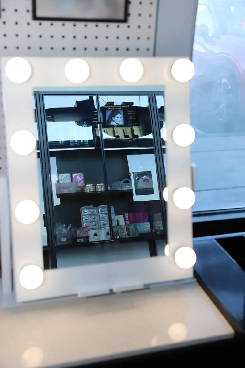 Lit vanity mirror at the front of the salon.